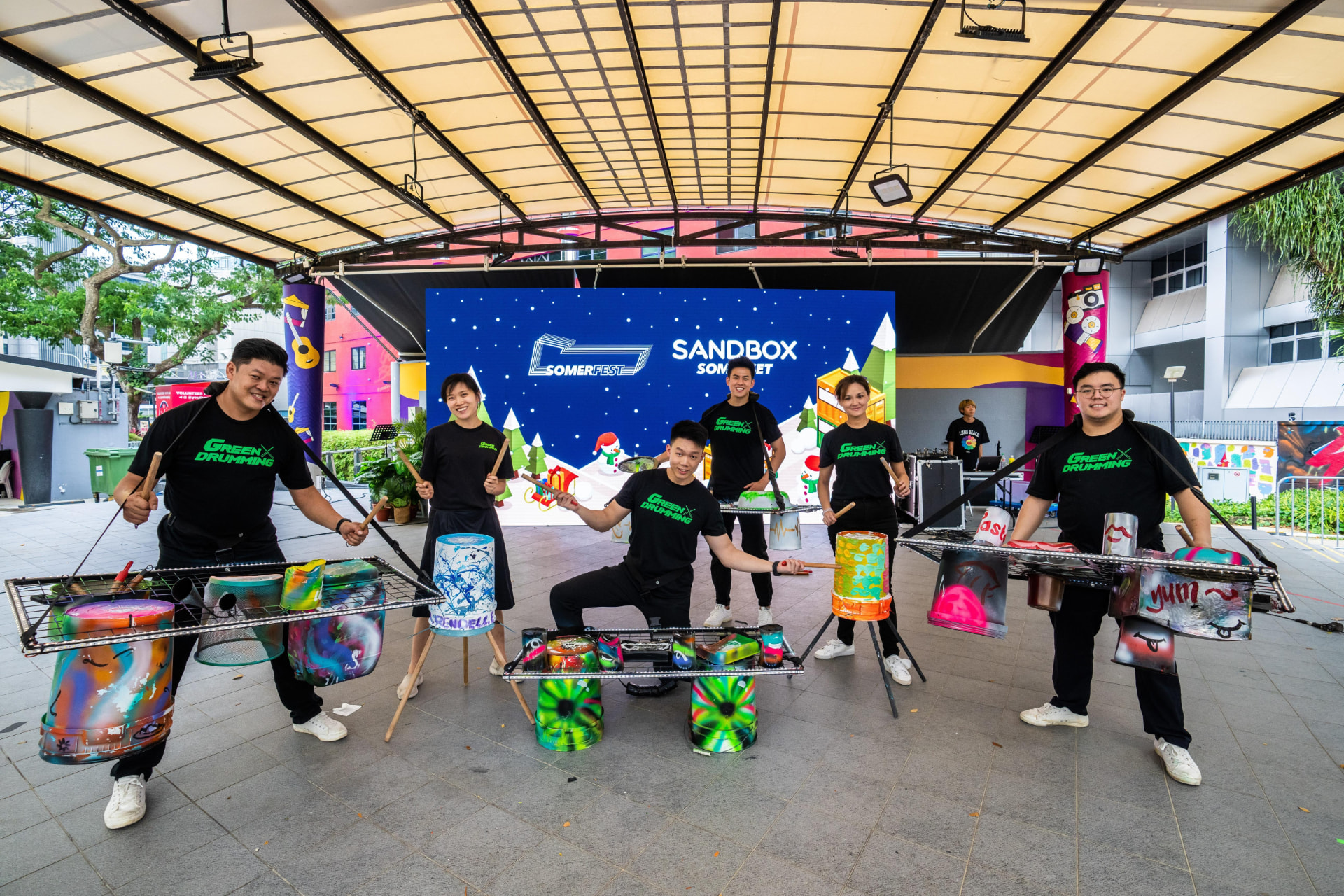 Green Drumming performers with colourful upcycled drums at an outdoor stage