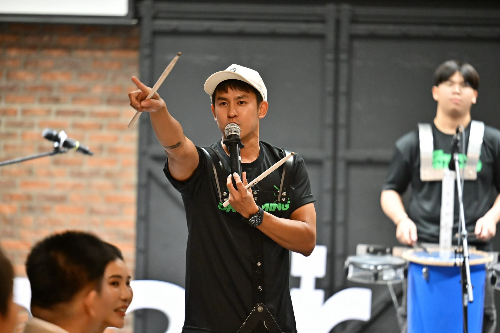 Arthur Choo leading a drumming session with microphone and drumsticks